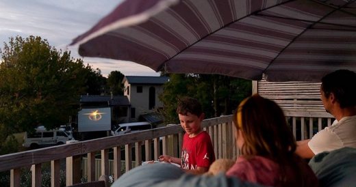 Community Stays Connected With Outdoor Movie That Can Be Watched From People’s...