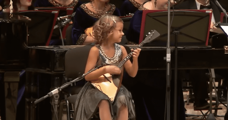 7-Year-Old Girl Leads Full Orchestra With Her Three-Stringed Instrument